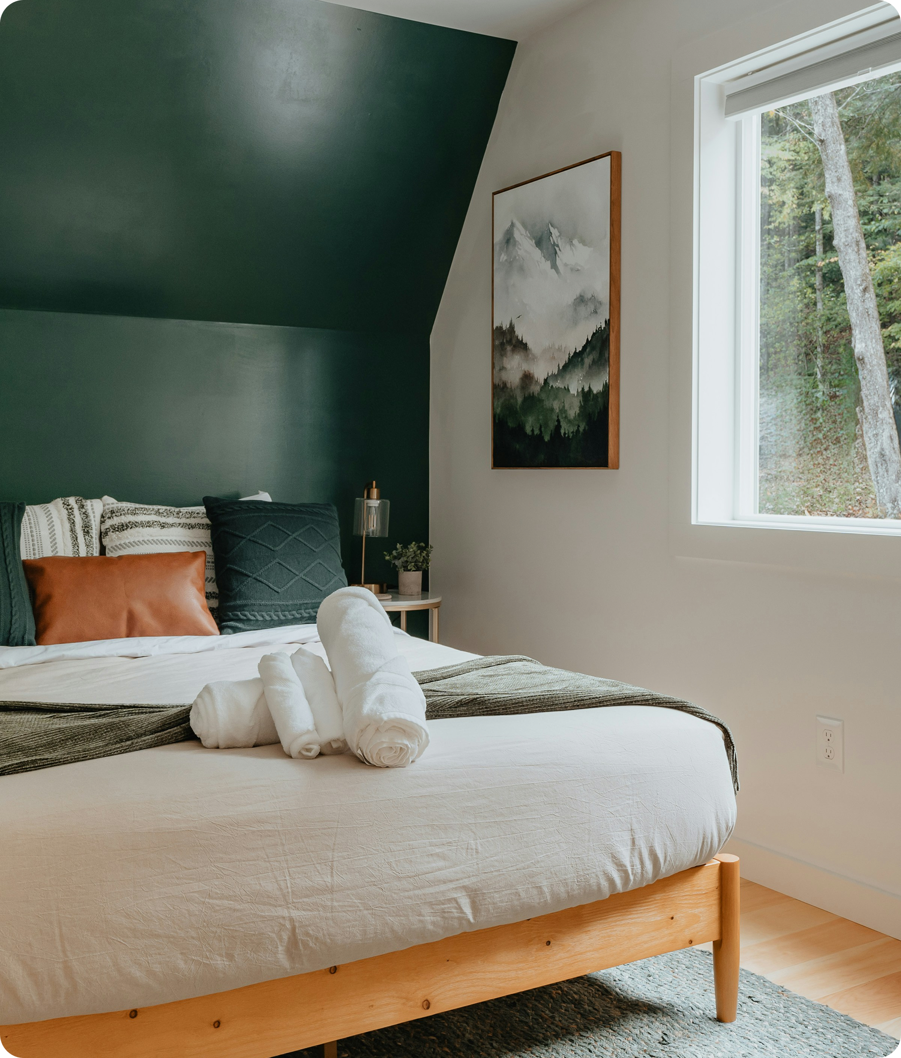 Acogedor dormitorio en una casa de alquiler de madera con toallas preparadas sobre la cama.