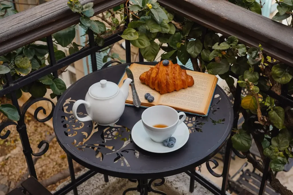 Ένα φλιτζάνι τσάι, ένα κρουασάν και μια κανάτα πάνω στο τραπεζάκι του μπαλκονιού σε ένα διαμέρισμα προς ενοικίαση – πρωινό στον καθαρό αέρα
