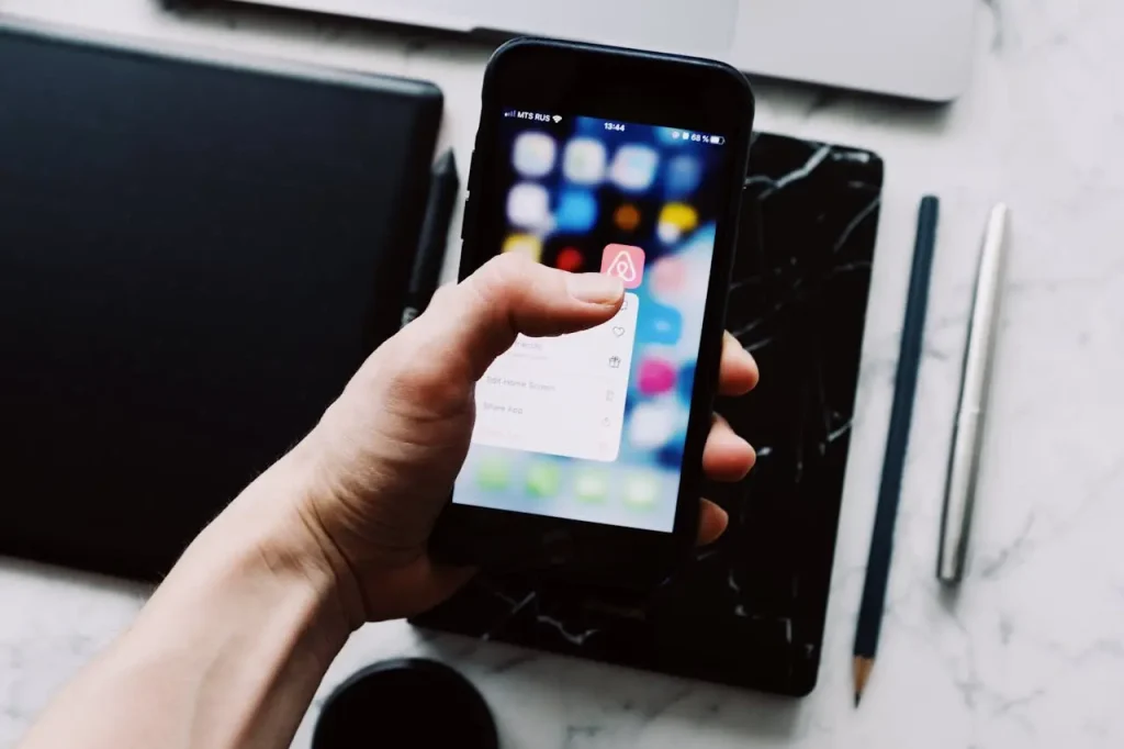 Smartfon z aplikacją Airbnb - zarządzanie ofertą i rezerwacjami przez aplikację mobilną gospodarza.
